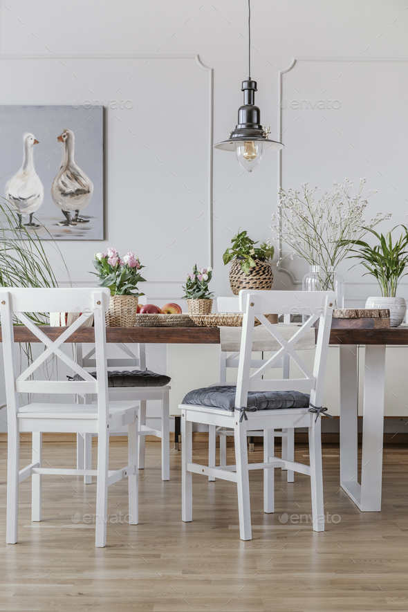 White chairs at wooden table in cottage dining room interior wit